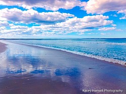 As the sky reflects off the water on the sand