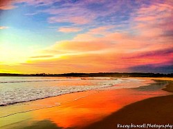 Sunrise over the ocean, the sky mirroring on the wet sand and water