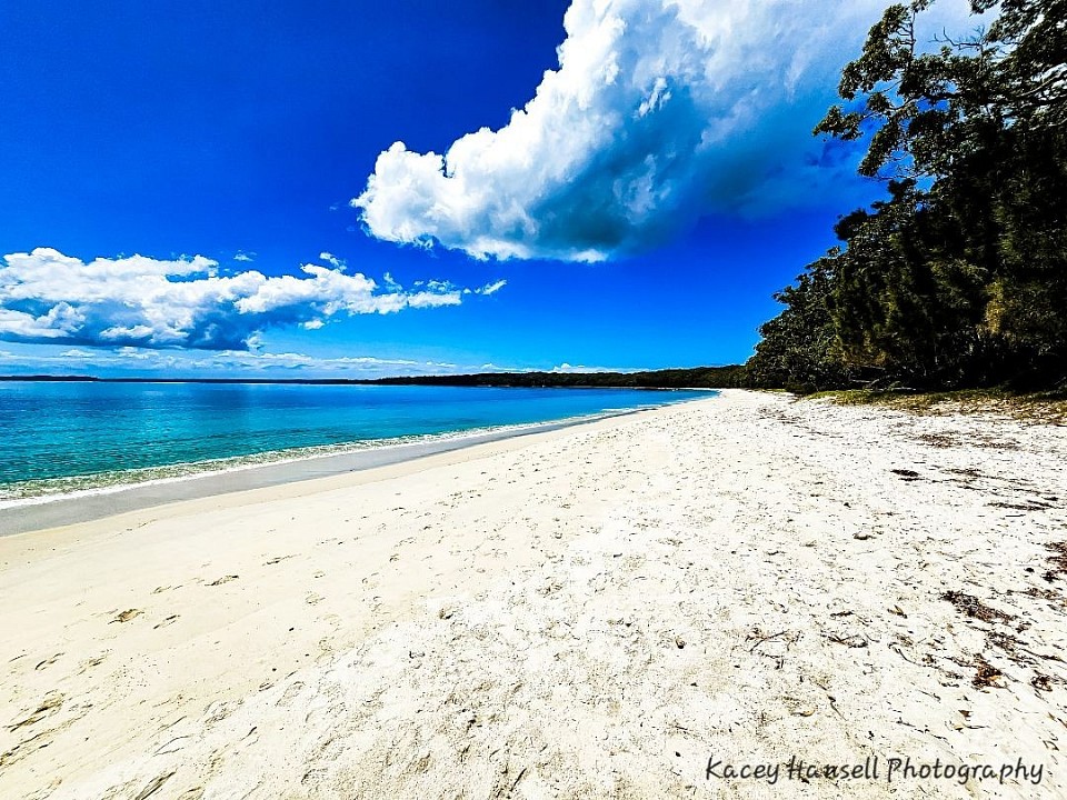 As the waves wash ashore on the white sand beach